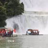 Du khách Việt Nam mang theo cờ Tổ quốc tham quan Khu hợp tác du lịch xuyên biên giới Thác Bản Giốc (Việt Nam)-Đức Thiên (Trung Quốc). (Ảnh: Công Tuyên/TTXVN)