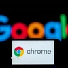 Biểu tượng Chrome trên màn hình điện thoại và biểu tượng Google (phía sau). (Ảnh: Getty Images/TTXVN)