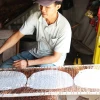 Anh Nguyễn Văn Tài ở ấp Hậu Thuận, xã Hậu Thành, huyện Cái Bè, tỉnh Tiền Giang đặt bánh vừa tráng vào vỉ để phơi khô. (Ảnh: Hữu Chí/TTXVN)