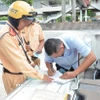 Cảnh sát giao thông lập biên bản một trường hợp tài xế xe khách vi phạm. (Ảnh: Linh Sơn/TTXVN)
