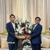 Đại sứ Phạm Việt Hùng (trái) tặng lãng hoa tới Đại sứ Lào Sisavath Inphachanh chúc mừng 50 năm Quốc khánh Lào. (Ảnh: Đỗ Sinh/TTXVN)