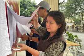 Cử tri phường Từ Liêm kiểm tra danh sách cử tri được niêm yết công khai tại khu vực bỏ phiếu. (Ảnh: Hằng Trần/Vietnam+)