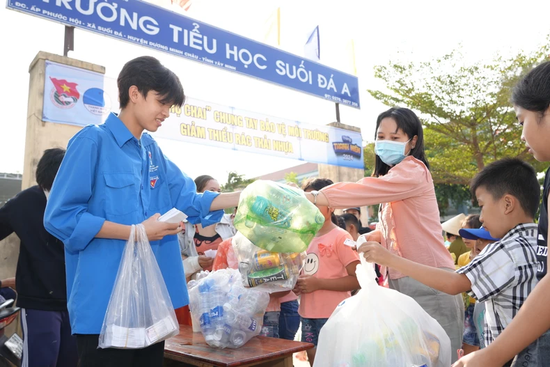 Đoàn viên Thanh niên xã Suối Đá thu gom chai nhựa sử dụng một lần và phát phiếu tham gia phiên chợ chai cho người dân. (Ảnh: Minh Phú/TTXVN)