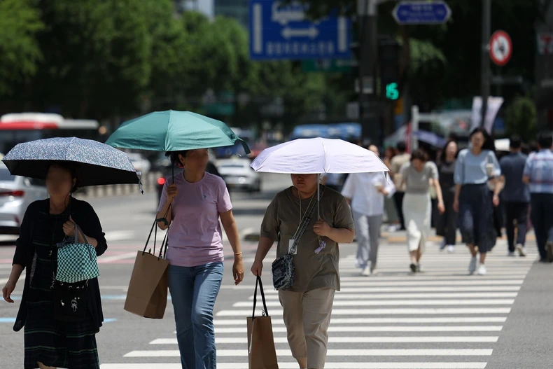 Người dân di chuyển trên đường phố dưới trời nắng nóng tại Seoul, Hàn Quốc. (Ảnh: Yonhap/TTXVN)