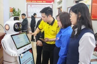 Cán bộ Trung tâm phục vụ hành chính công xã Quỹ Nhất hướng dẫn người dân thao tác trên Robot Lễ tân AI. (Ảnh: Công Luật/TTXVN)