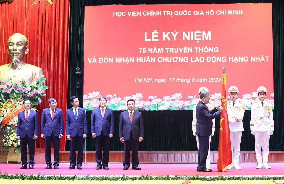 Tổng Bí thư, Chủ tịch nước Tô Lâm gắn Huân chương Lao động hạng Nhất lên lá cờ truyền thống của Học viện Chính trị Quốc gia Hồ Chí Minh. (Ảnh: Trí Dũng/TTXVN)