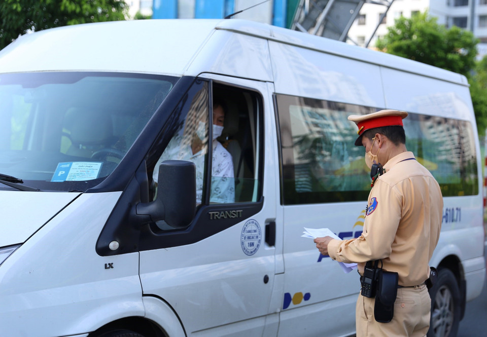 Lực lượng chức năng kiểm tra giấy tờ của người đi qua chốt kiểm soát cầu Nhật Tân. (Ảnh: Hoàng Hiếu/TTXVN)