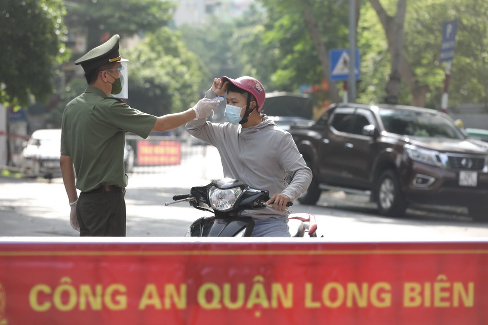 Lực lượng chức năng kiểm tra thân nhiệt người qua chốt kiểm soát cầu Long Biên. (Ảnh: Minh Quyết/TTXVN)