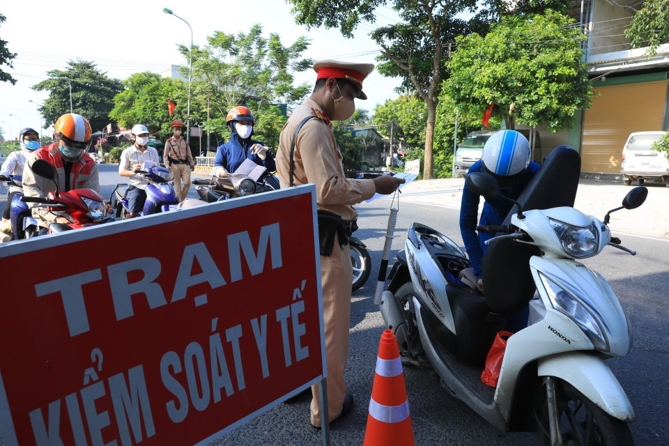 Lực lượng chức năng kiểm tra giấy đi đường của người dân tại chốt số 14 cầu Thạch Bích. (Ảnh: Tuấn Anh/TTXVN)