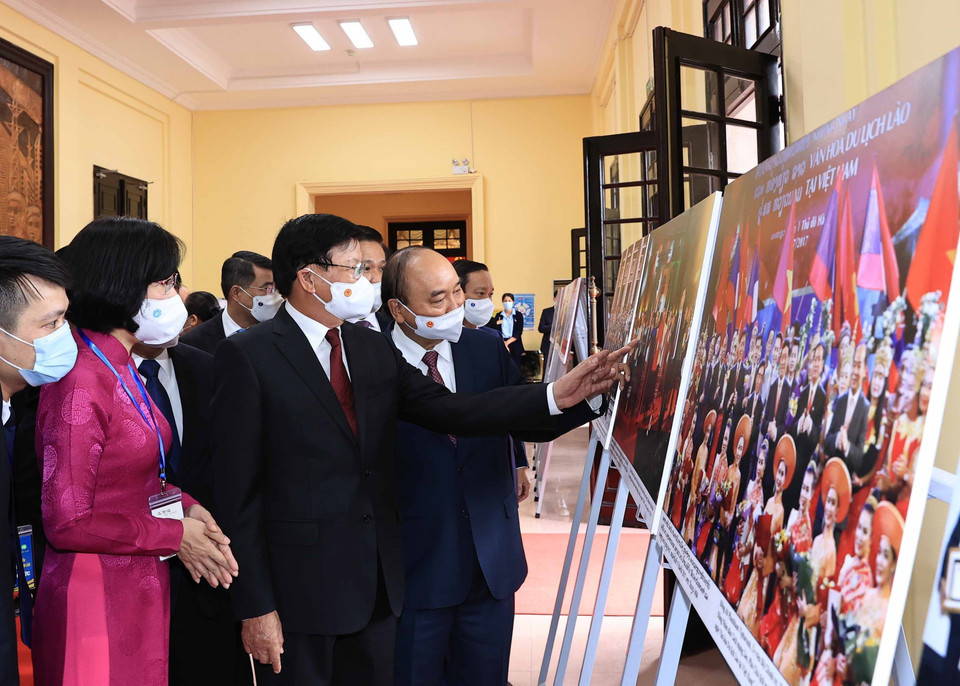 Phó Tổng Giám đốc Thông tấn xã Việt Nam Vũ Việt Trang giới thiệu trưng bày ảnh 'Quan hệ hữu nghị vĩ đại, đoàn kết đặc biệt và hợp tác toàn diện Việt Nam-Lào' với Tổng Bí thư, Chủ tịch nước Lào Thongloun Sisoulith và Chủ tịch nước Nguyễn Xuân Phúc. (Ảnh: Thống Nhất/TTXVN)