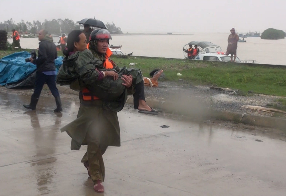 Lực lượng cứu nạn đưa người dân ra khỏi vùng lũ. (Ảnh: TTXVN)