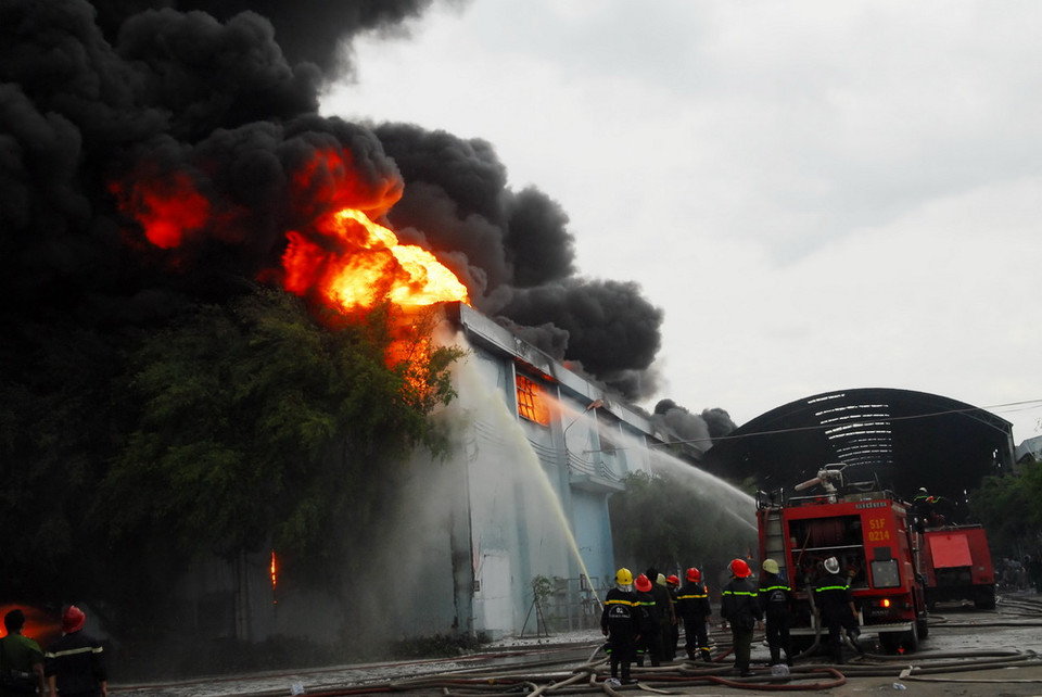 Kho hàng chứa nguyên vật liệu và các sản phẩm dễ cháy, cao su, nên công tác chữa cháy gặp nhiều khó khăn. (Ảnh: Mạnh Linh/TTXVN)