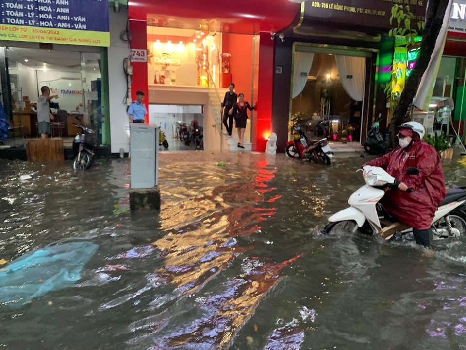 Nước ngập tràn vào nhà dân và cơ sở kinh doanh trên đường Lê Hồng Phong - Quận 10. (Ảnh: Hồng Giang/TTXVN)