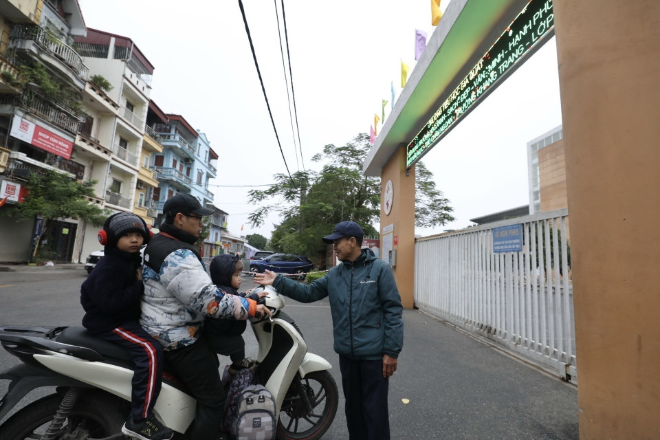 Nhân viên bảo vệ nhắc phụ huynh cho học sinh về khi nhiệt độ dưới 10 độ C. (Ảnh: Minh Quyết/TTXVN)