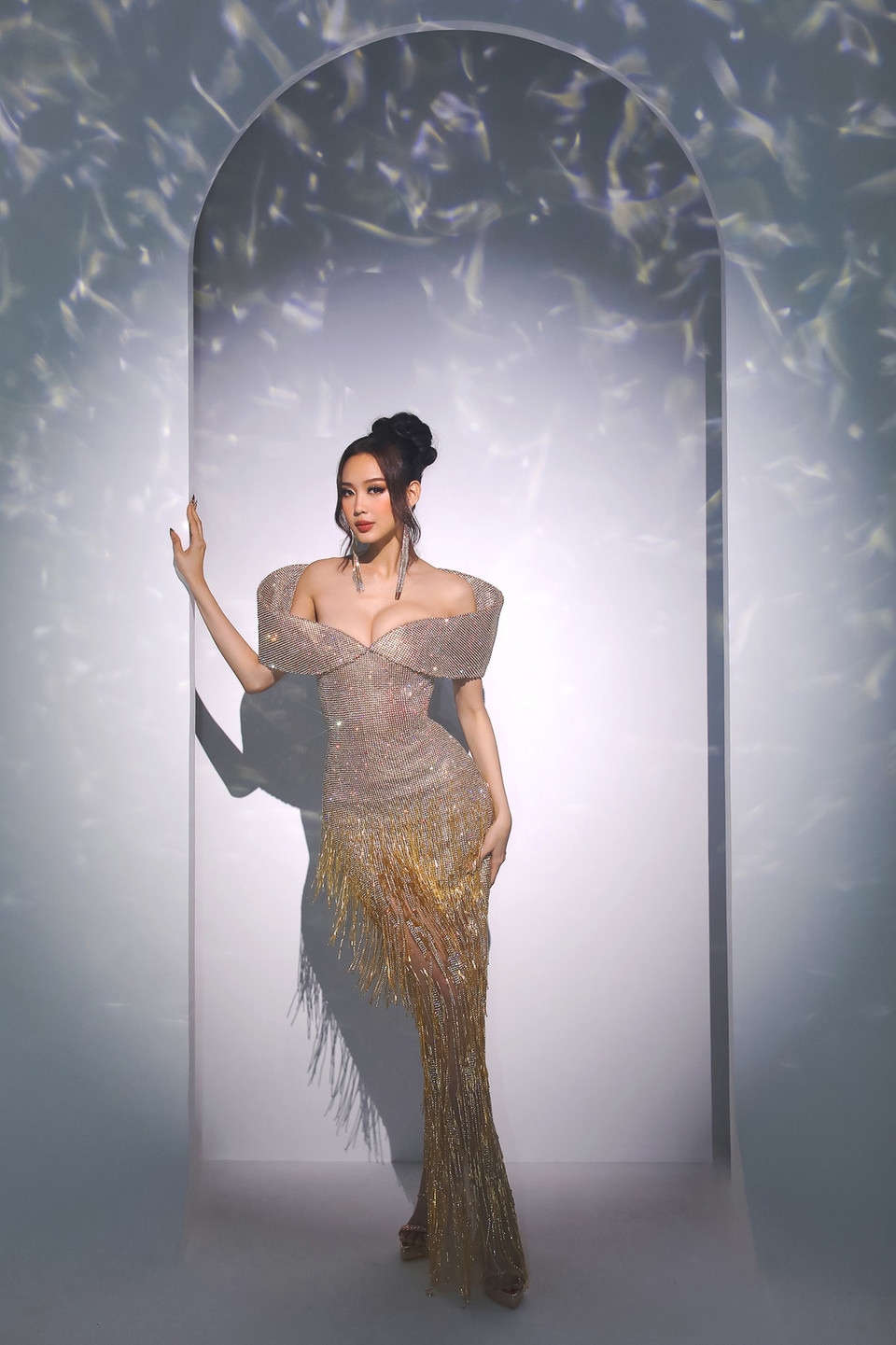 Chiếc đầm với tông màu vàng gold chủ đạo, đính kết hàng nghìn hạt đá, kết hợp với phom dáng kiểu trễ vai bản lớn giúp nâng vẻ hoành tráng khi nhìn từ phía sau. (Ảnh: CTV/Vietnam+)