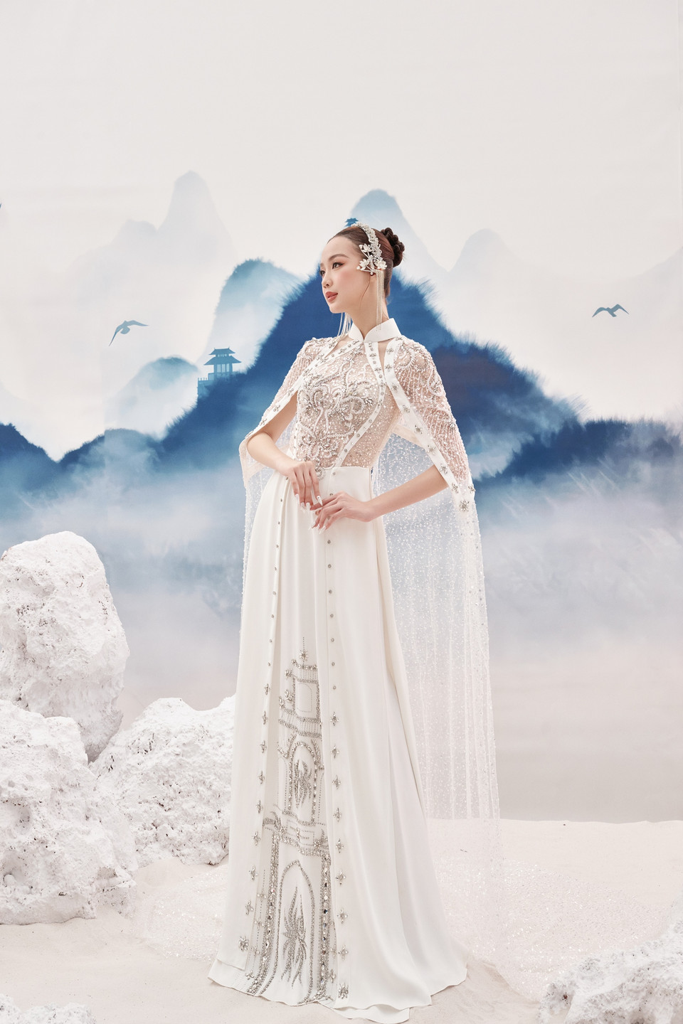 Với tông màu trắng, khắc họa hình ảnh Đại nội Kinh thành Huế lộng lẫy, tà Áo dài được đính kết hàng nghìn viên đá trong hơn 200 giờ công lao động, đã góp phần tôn vinh vẻ đẹp sang trọng, xa hoa cho bộ trang phục cùng chiếc áo choàng tượng trưng cho quyền lực, uy nghiêm nhưng không kém phần thanh lịch. (Ảnh: CTV/Vietnam+)