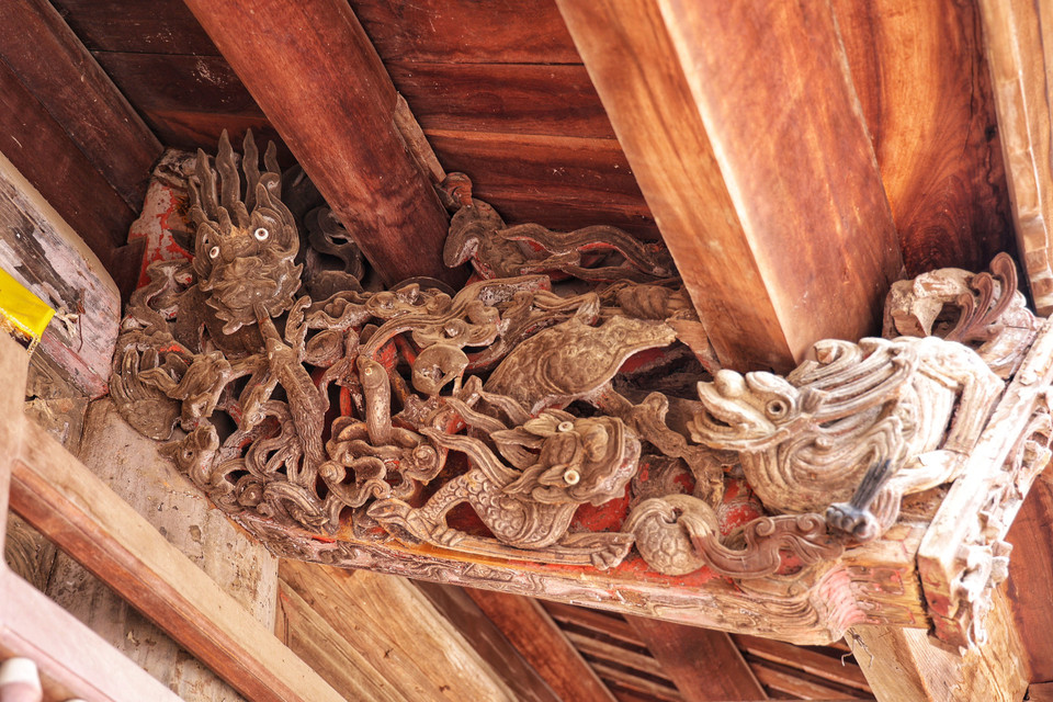Những đầu dư của các xà ở gian chính và những kẻ hiên là những trọng điểm để trang trí. Những môtíp trang trí như rồng, hổ, cá, chim, hoa lá, mây,... đều được chạm nổi, chạm lộng hoặc chạm ren. (Ảnh: Xuân Mai/Vietnam+)