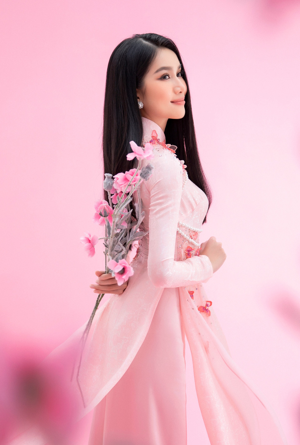 Thiết kế áo dài cách điệu bằng phần hạt ngọc trai chạy viền trên nền lụa hồng khiến tổng thể nhan sắc hai người đẹp càng thêm duyên dáng. (Ảnh: CTV/Vietnam+)