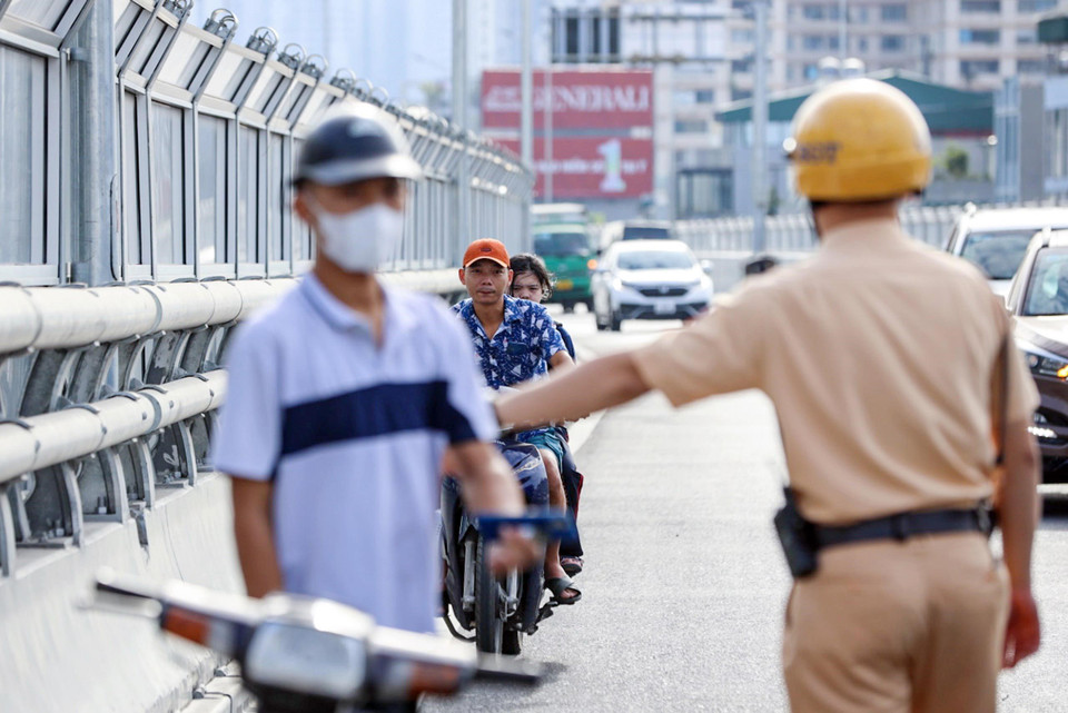 Lực lượng CSGT dừng xe kiểm tra và xử lý các trường hợp người điều khiển xe máy đi vào đường Vành đai 2 trên cao. (Ảnh: Phạm Kiên/TTXVN)