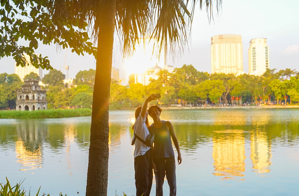 Du khách nước ngoài lưu lại khoảnh khắc mùa Thu bên hồ Hoàn Kiếm. (Ảnh: Khánh Hoà/TTXVN)