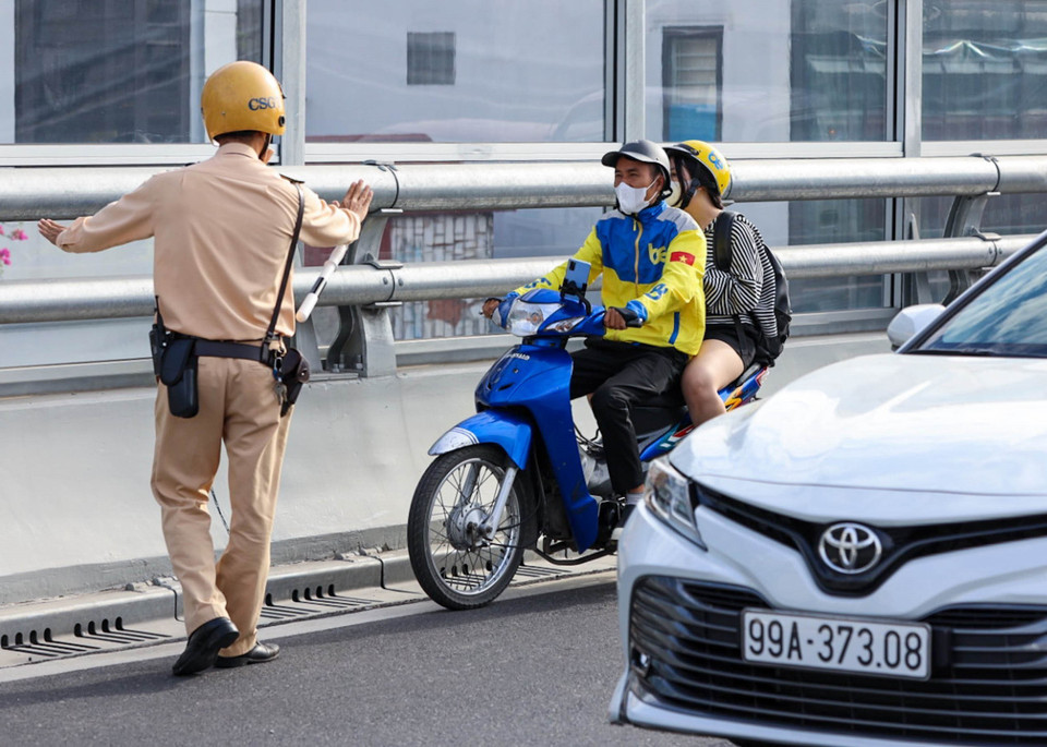 Lực lượng CSGT dừng xe kiểm tra và xử lý các trường hợp người điều khiển xe máy đi vào đường Vành đai 2 trên cao. (Ảnh: Phạm Kiên /TTXVN)