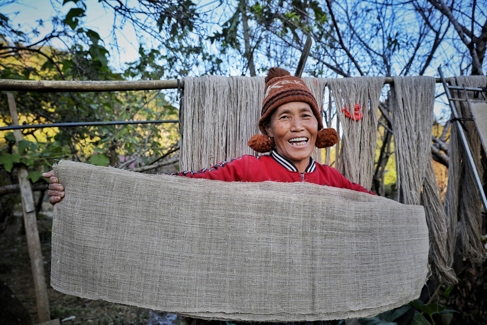 Sau khi dệt thành tấm vải lanh thô như thế này, bà Chai cho biết sẽ tiếp tục lăn cho vải mềm bóng ra. Việc lăn vải rất kỳ công. Bà Chai phải dùng một thân gỗ to mịn, cùng với tấm ván to bằng mảnh vải, dài khoảng 1m, đặt miếng vải giữa tấm ván và thân gỗ rồi đứng lên tấm ván lăn qua lăn lại, cứ thế khi nào thấy đạt thì tiếp tục xê dịch dần tấm vải cho đến hết. Khi tấm vải đã mềm, mịn, bóng mới mang đi ngâm với nước tro. Ngâm khoảng 1 tuần thì lấy ra giặt, phơi khô, cứ như vậy khi nào tấm vải có trắng ngà mới thôi. (Ảnh: Xuân Mai/Vietnam+)