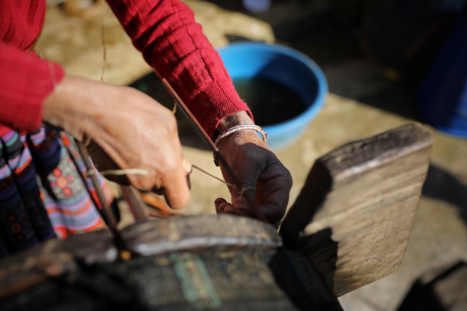 Một đầu sợi lanh nối vào khung tre có nhiều lỗ, còn một đầu buộc vào lõi con quay. (Ảnh: Xuân Mai/Vietnam+)