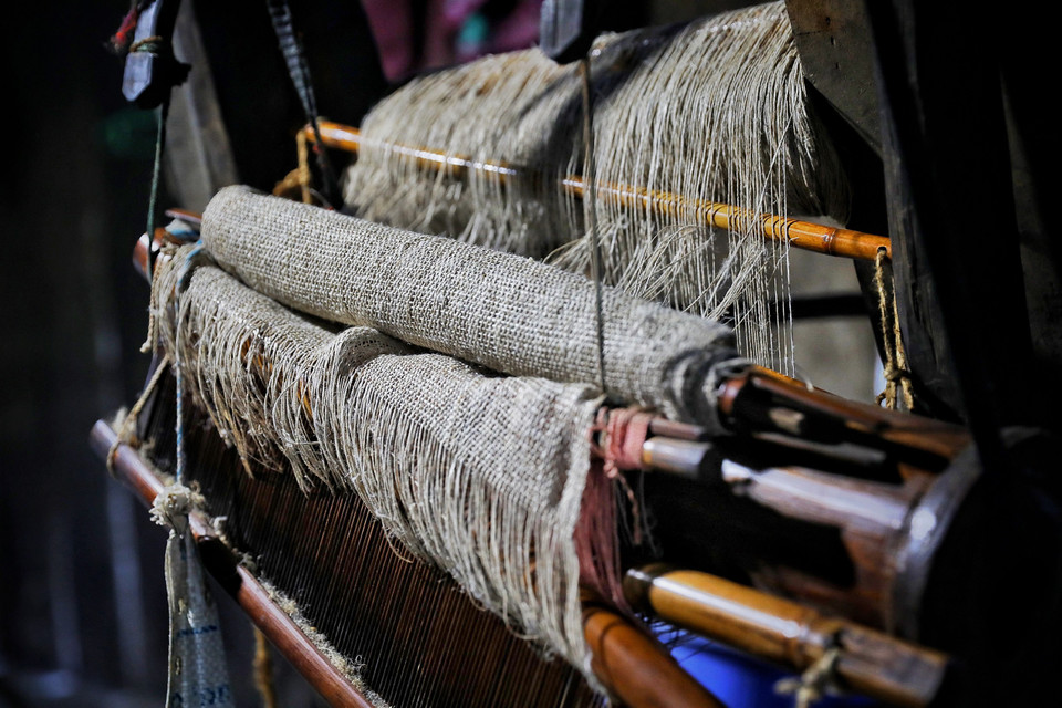 Chiếc khung dệt vải được buộc vào một cột nhà. Sau mỗi lần ngồi dệt, bà Chai lại buộc gọn gàng để tiếp tục công việc vào hôm sau hoặc bất kỳ lúc nào bà rảnh. (Ảnh: Xuân Mai/Vietnam+)