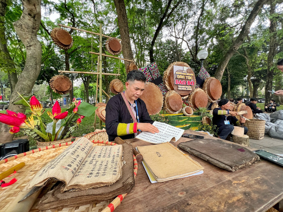 Nghệ nhân dân gian chuyên bảo tồn các thứ tiếng và chữ viết cổ của các tộc người thiểu số, ông Tẩn Vần Siệu giới thiệu các bài cúng của người Dao được lưu lại trong các bản ghi chép cổ. (Ảnh: Mai Mai/Vietnam+)