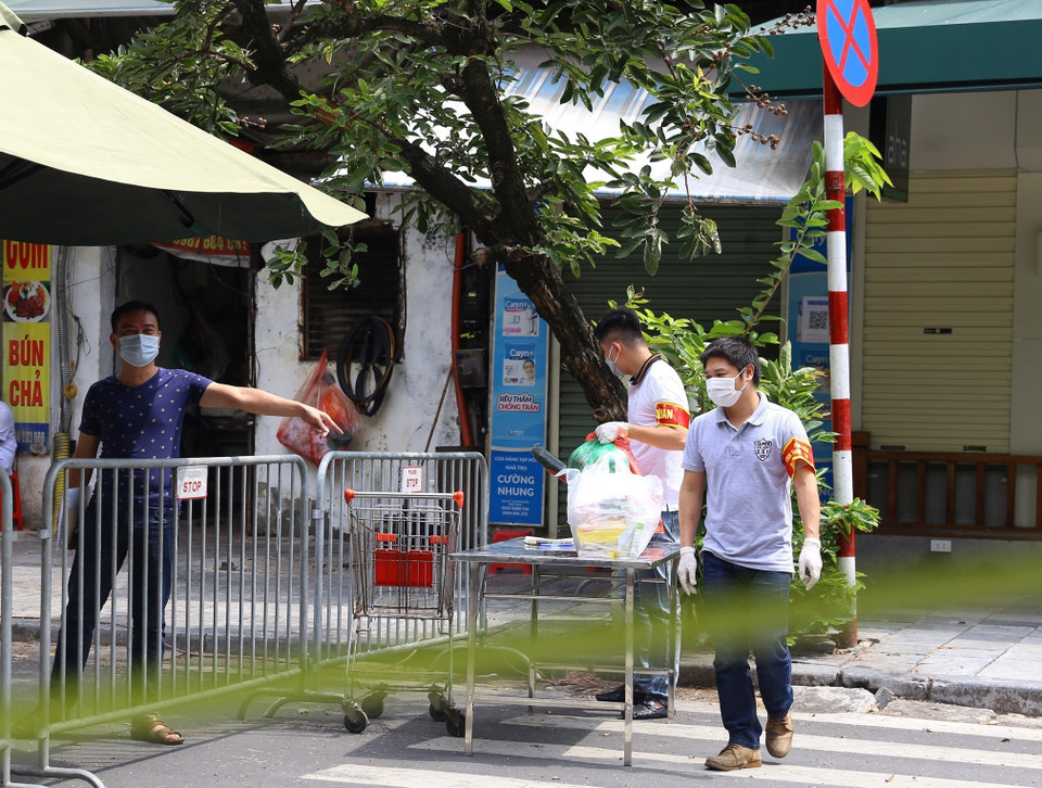 Vận chuyển hàng hóa tiếp tế vào cho người dân trong khu vực bị phong tỏa phố Phủ Doãn. (Ảnh: Hoàng Hiếu/TTXVN)