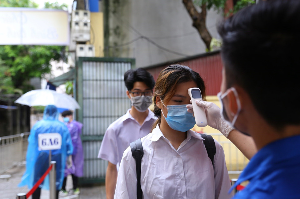  Đo thân nhiệt thí sinh tại điểm thi Trường THCS Hà Huy Tập (quận Hai Bà Trưng). (Ảnh: Hoàng Hiếu/TTXVN)