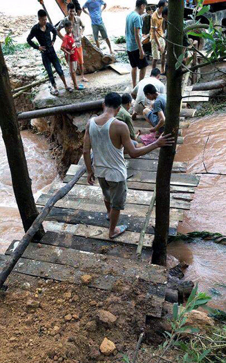 Người dân làm cầu tạm đi qua các điểm lũ. (Ảnh: Văn Đức/TTXVN)