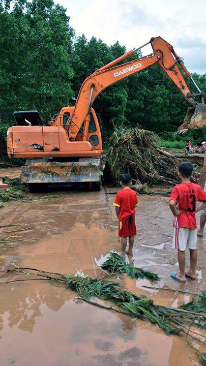 Huy động máy xúc san gạt đất đá, cây đổ để khơi thông dòng chảy. (Ảnh: Văn Đức/TTXVN)