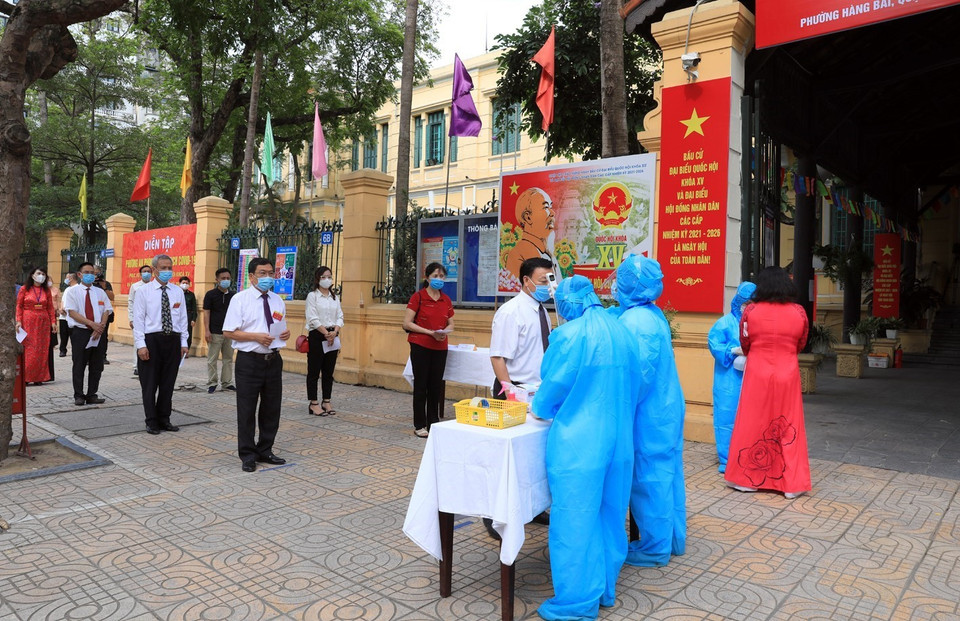 Các cử tri đi bầu cử được kiểm tra thân nhiệt và xếp hàng giữ khoảng cách tại điểm bầu cử. (Ảnh: Phan Tuấn Anh/TTXVN)