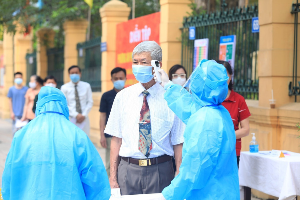 Các cử tri được đo thân nhiệt trước khi vào bỏ phiếu. (Ảnh: Phan Tuấn Anh/TTXVN)