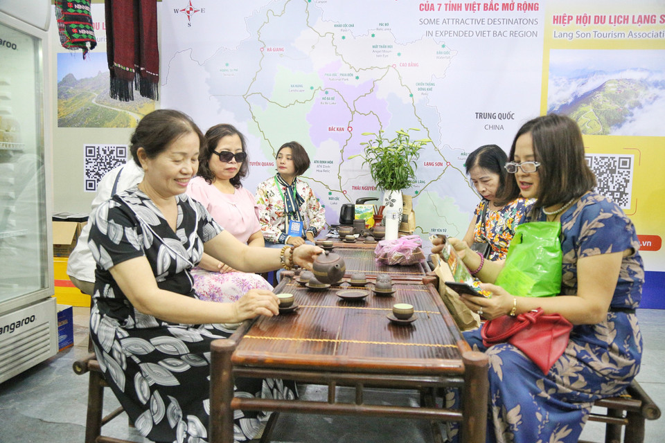 Khách tham quan thích thú thưởng thức đặc sản trà mạn được giới thiệu tại hội chợ. (Ảnh: Nhật Lam/Vietnam+)