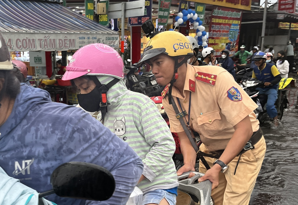 CSGT giúp người dân vượt qua vùng trũng, ngập úng sâu ở đoạn Quốc lộ 50 - Nguyễn Văn Linh, Quận 8. (Ảnh: Thanh Vũ/TTXVN)