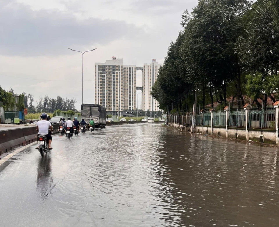 Nước ngập sâu khiến nhiều phương tiện phải di chuyển sát dải phân cách để tránh nước tràn vào động cơ. (Ảnh: TTXVN phát)