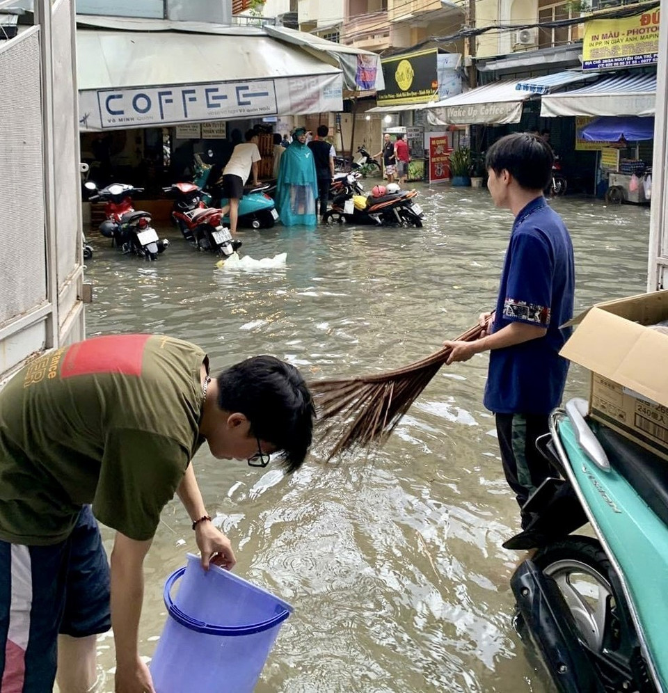 Người dân trên đường Nguyễn Gia Trí, quận Bình Thạnh vất vả tát nước ngập tràn vào nhà. (Ảnh: Hồng Giang/TTXVN)