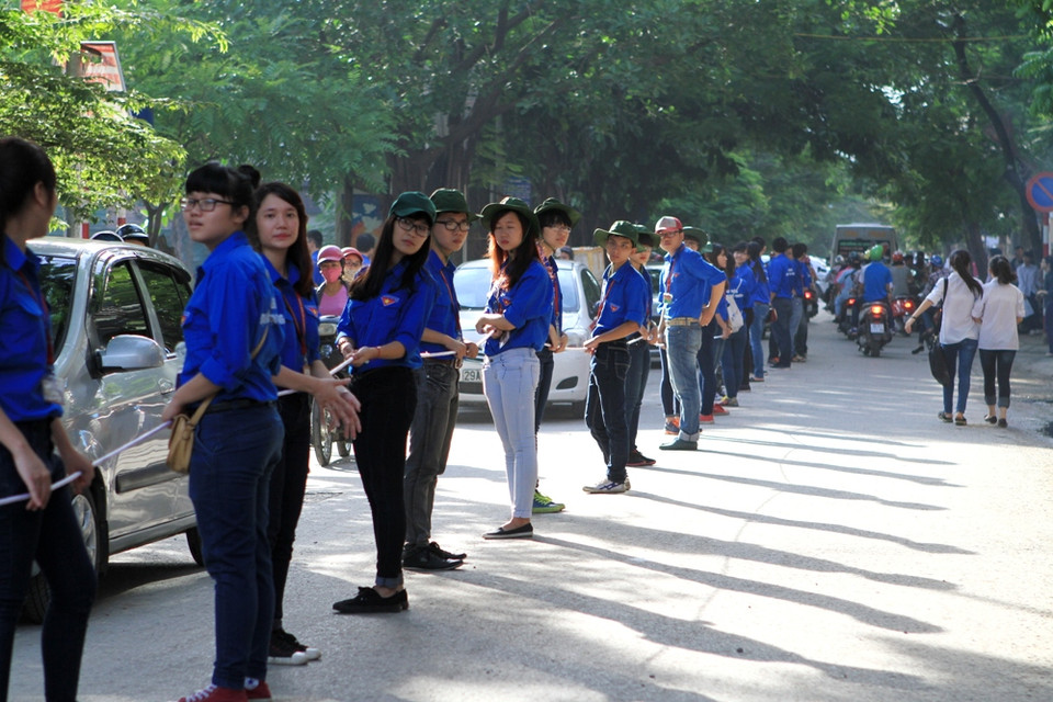 Sinh viên tình nguyện Đại học Ngoại Thương đứng phân làn giao thông dài cả trăm mét trước cổng trường. (Ảnh: Xuân Mai/Vietnam+)