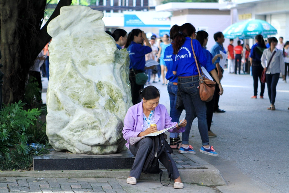 Một phụ huynh ngoại tỉnh đưa con về Thủ đô thi vừa tranh thủ đợi con vừa nghiên cứu bản đồ Hà Nội. (Ảnh: Xuân Mai/Vietnam+)