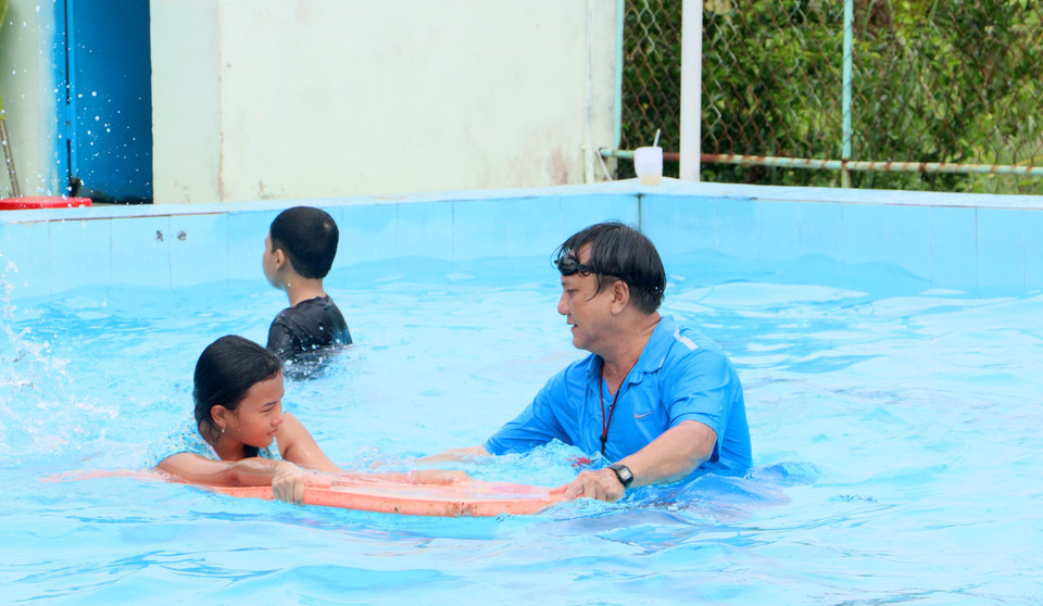 Giáo viên hỗ trợ thiếu nhi tập bơi. (Ảnh: Lê Thúy Hằng/TTXVN)