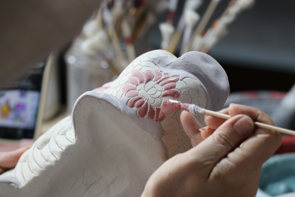 Nghệ nhân chấm men và vẽ họa tiết trên sản phẩm gốm Biên Hòa tại lò gốm Phong Sơn. (Ảnh: Sỹ Tuyên /TTXVN)