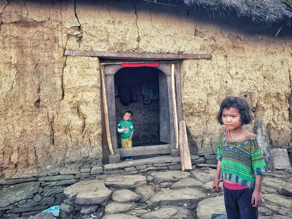 Những đứa trẻ hết ngồi rồi đứng rồi lại lúi húi tự xúc bát cháo loãng. Chúng chơi với nhau, ngóng cha mẹ đi ruộng ngày mùa về, thi thoảng mới nghe tiếng chí chóe nhau. (Ảnh: Xuân Mai/Vietnam+)