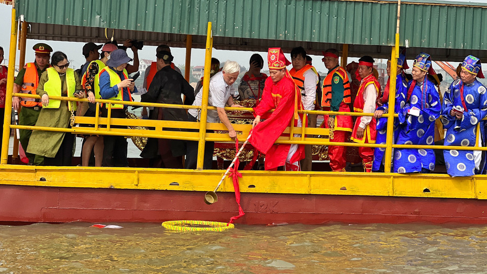 Trước khi lấy nước, người ta thả một vòng tròn quấn vải đỏ hoặc nhiều màu xung quanh xuống mặt nước, để xác định vị trí lấy nước và ngăn những gì không sạch sẽ trôi vào trong. Theo tín ngưỡng địa phương, khi lấy nước chỉ múc trong vòng tròn này thì mới linh thiêng, sau đó đổ nước vào chóe cũng qua một tấm vải đỏ. (Ảnh: Mai Mai/Vietnam+)