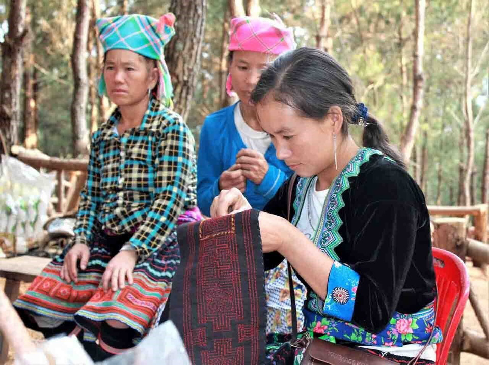 Bà con dân tộc Mông mang sản phẩm thổ cẩm tự tay làm để phục vụ du khách. (Ảnh: Công Tuyên/TTXVN)