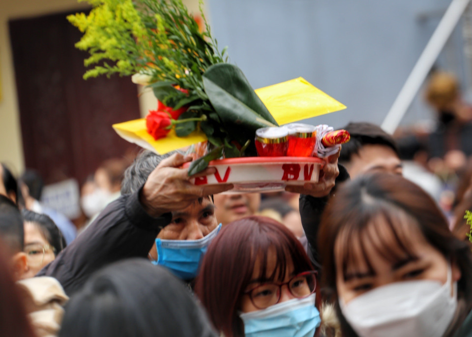 Nhiều người phải đội lễ lên đầu để di chuyển vào trong phủ. (Ảnh: Tuấn Đức/TTXVN)