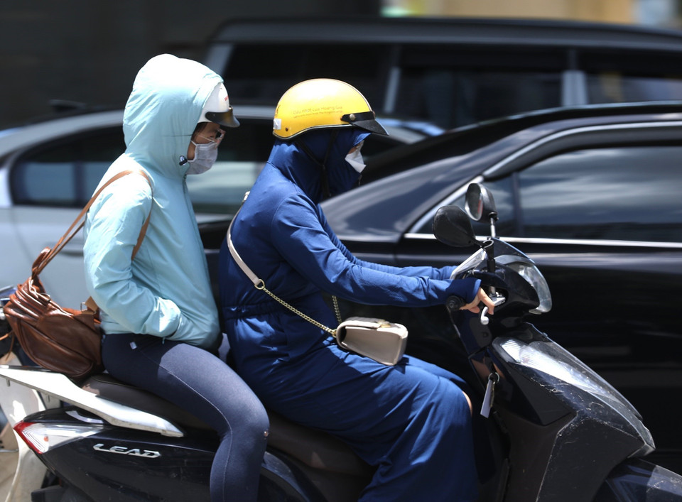 Người dân vẫn khó chịu khi phải di chuyển dù đã mặc quần áo tránh nóng. (Ảnh: Hoàng Hiếu/TTXVN)