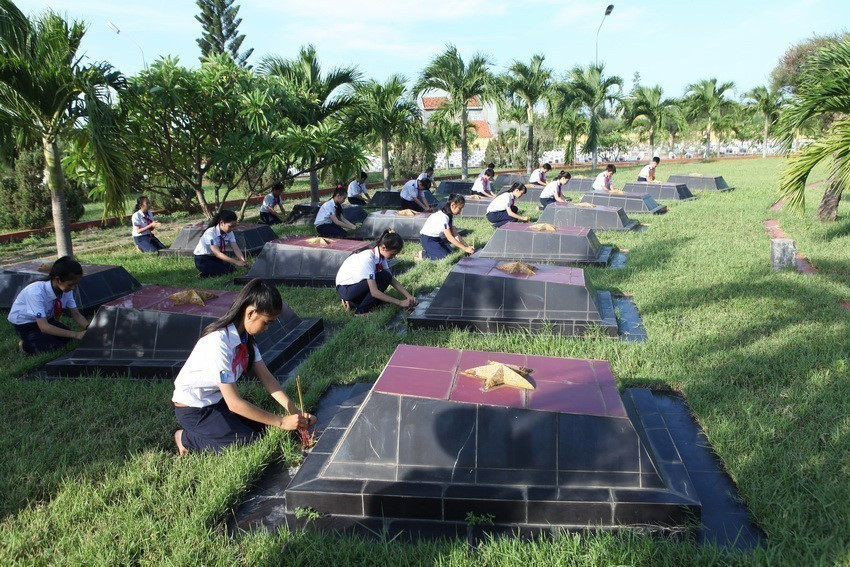 Học sinh trường THCS Trần Hưng Đạo, tỉnh Phú Yên chăm sóc phần mộ liệt sĩ tại Nghĩa trang liệt sỹ Đông Tác. (Ảnh: Anh Tuấn/TTXVN)