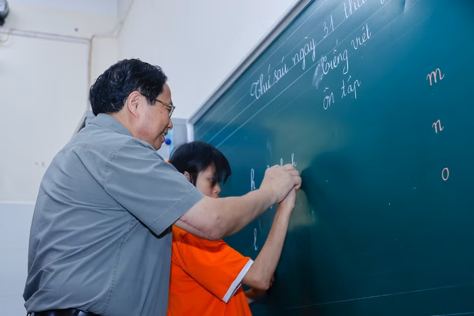 Thủ tướng Phạm Minh Chính tham gia tiết học tiếng Việt cùng trẻ em tại Trung tâm Nuôi dưỡng trẻ khuyết tật Hà Nội. (Ảnh: Dương Giang/TTXVN)